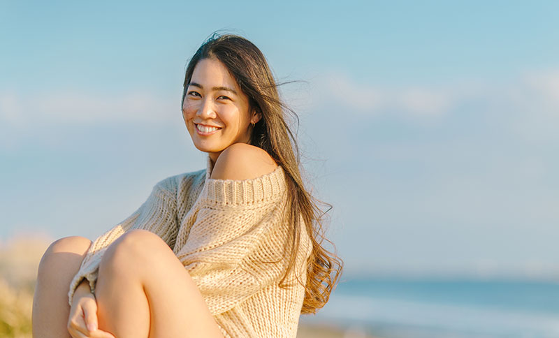 young lady smiling at the beach after a visit to Brush & Floss Dental Center in Stratford, CT