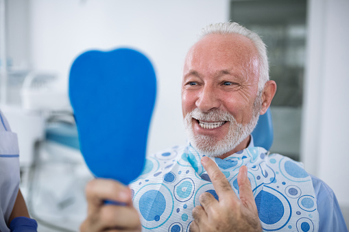 Older man examining his mouth after oral surgery at Brush & Floss Dental Center in Stratford, CT