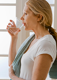 Middle aged woman drinking water.