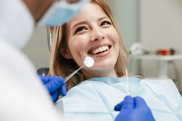White female patient happily waiting in a dental chair for her dentist to begin her routine dental exam.