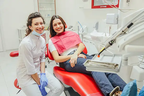 A dentist smiling brightly while talking about all on 4 dental implants with her seated patient at Brush & Floss Dental Center in Stratford, CT